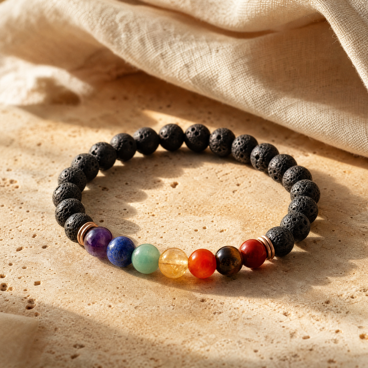 Bracelet 7 chakras en perles de pierres colorées, en gros plan sur travertin