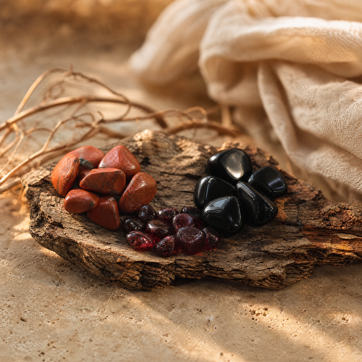 Jaspe rouge, grenat et obsidienne sur écorce, pierres du chakra racine, sur travertin