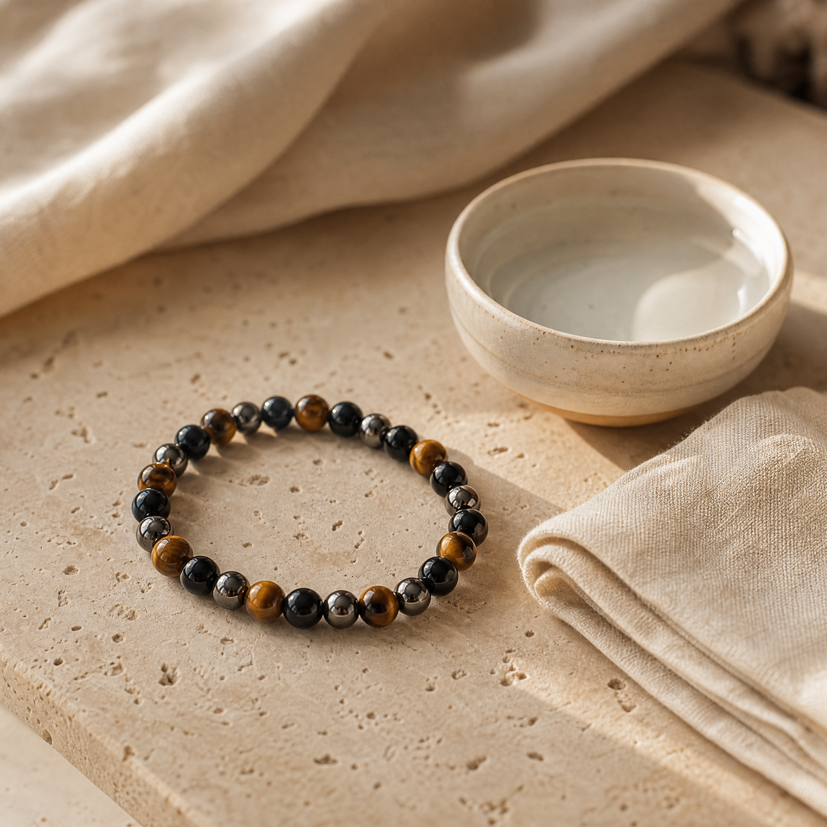 Bracelet triple protection œil de tigre, hématite et obsidienne avec bol d'eau et chiffon doux, sur travertin