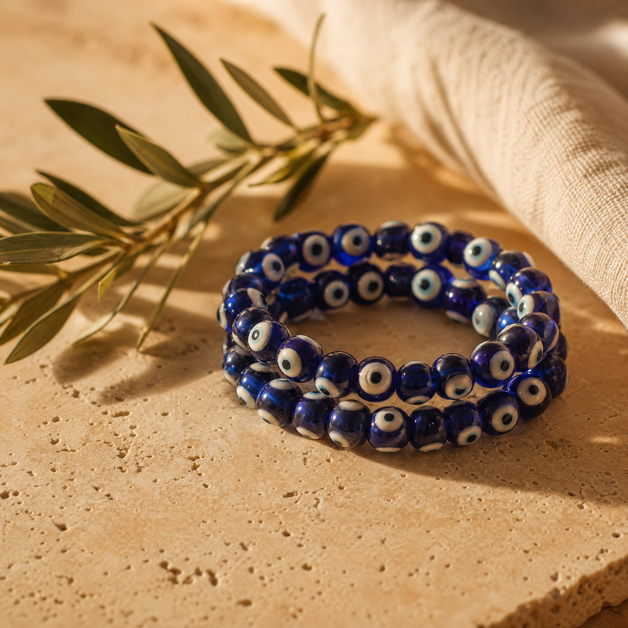 Bracelet d'œil grec en perles de verre bleu avec branche d'olivier, sur travertin