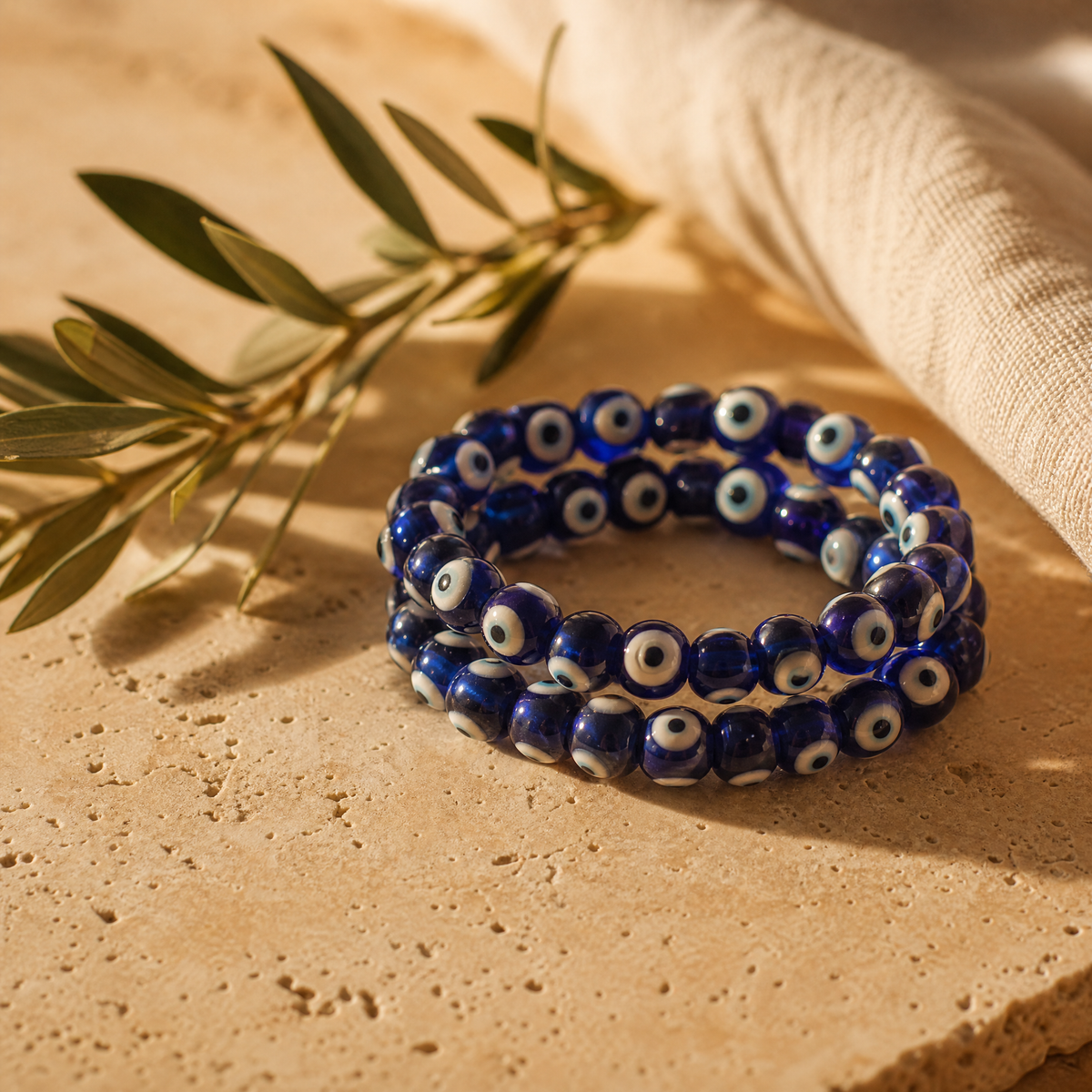 Bracelet d'œil grec en perles de verre bleu avec branche d'olivier, sur travertin